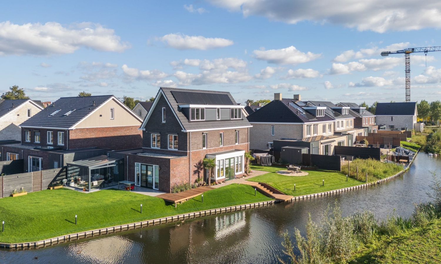 Moderne tuin aan het water in Pijnacker, ontworpen en aangelegd door Keko Hoveniers. De tuin heeft een strak gazon, houten vlonders bij het water en een sfeervol terras.